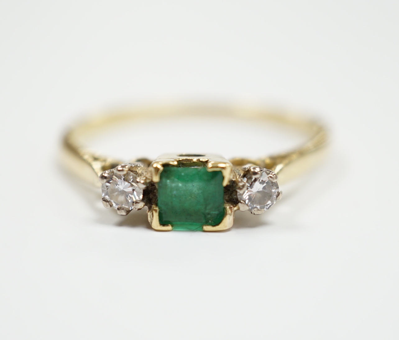 An 18ct and plat, single stone emerald and two stone diamond set ring, size Q/R, gross weight 2.6 grams.